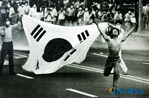 【서울=뉴시스】 1987년6월26일. 6.26 평화대행진이 벌어진 부산 문현로터리에서 웃옷을 벗은 한 시민이 "최루탄을 쏘지 마라"고 외치며 다탄두최루탄을 발사하는 경찰에게 달려가고 있다. 6월민주화운동, 6.10민주항쟁이라고도 부르는 1987년 민주화운동은 '4.13호헌'조치를 통해 국민의 민주화 열망을 억압하고 장기집권 획책에 대항하면서 시작됐다. 1987년 6월10일 국민운동본부는‘박종철 고문살인 은폐조작 규탄 및 민주헌법쟁취 범국민대회’를 개최하여 6월항쟁의 기폭제가 되었으며 6월26일 민주헌법쟁취대행진이 전국적으로 벌어졌다. '아, 나의조국'은 1999년 AP가 선정한 20세기 100대 사진에 포함됐다.(보도사진집 '그날그거리)/고명진기자 photodesk@newsis.com
