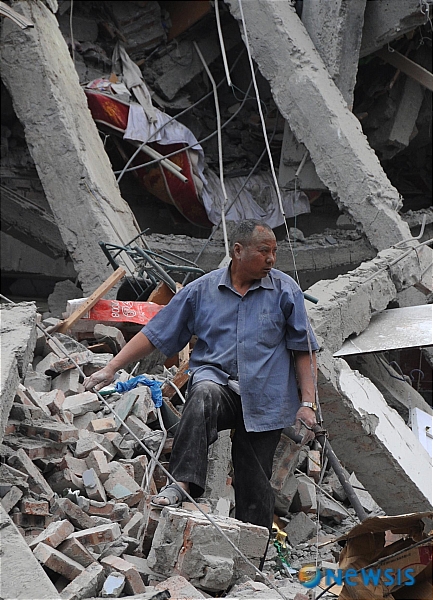 【두장얀(중국 쓰촨성)=신화/뉴시스】&nbsp; 규모 7.8의 강진이 엄습한 중국 남서부 쓰촨성의 두장얀에서 12일 한 주민이 붕괴된 건물 잔해 속에서 자신의 재산을 찾고 있다. 이날 오후 2시28분(현지시간) 발생한 이번 지진으로 베이촨현 한 곳에서만 3000∼5000명의 사망자가 발생했으며 7곳의 학교와 병원이 붕괴돼 학생들과 환자들이 매몰됨으로써 사망자 수는 더욱 늘어날 것으로 우려되고 있다.