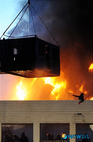 【서울=뉴시스】 20일 새벽 서울 용산 4구역 철거민대책위원회 회원들이 재개발에 따른 적절한 보상을 요구하며 밤샘 농성을 벌이고 있는 한강로 재개발지역의 한 건물 옥상에서 경찰의 강제 진압이 진행된 가운데 시위대가 옥상에 설치한 망루가 불에 타고 있다. 한 농성 철거민이 안에 사람이 있다며 불타는 망루를 가리키고 있다. /이광호기자 skitsch@newsis.com