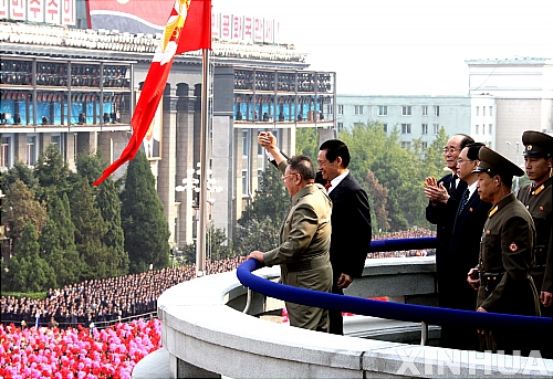 【평양=신화/뉴시스】북한 김정일 국방위원장이 10일 평양 시내에서 열린 조선노동당 창건 65주년 기념 군 퍼레이드를 참관 도중 손을 들어 인사하고 있다. 김 위원장과 손을 잡은 이는 중국 사절단인 저우융캉 공산당 정치상무국 위원이다.
