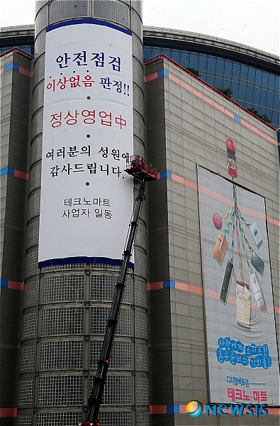 【서울=뉴시스】박동욱 기자 = 건물 흔들림 현상으로 안전점검으로 인해 퇴거명령이 내려졌던 테크노마트가 7일 오전 일부 영업재개가 실시된 가운데 서울 구의동 테크노마트 건물 외벽에 관계자들이 영업재개를 알리는 현수막을 설치하고 있다. fufus@newsis.com