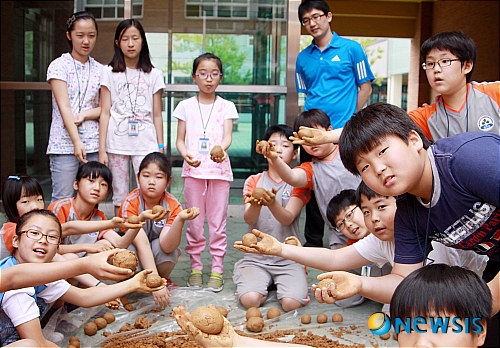 【양산=뉴시스】안지율 기자 = 경남 양산시 황산초등학교가 지난 7일 관내 YWCA, E마트와 함께 1사 1하천 살리기 운동의 하나로 새들천에서 흙 공던지기 이색 행사를 열었다. 사진은 학생들이 흙 공을 만들고 있다. (사진=양산 황산초 제공) photo@newsis.com