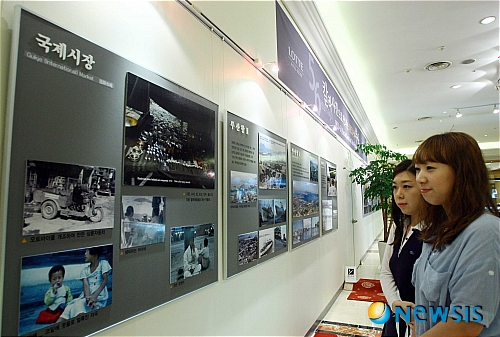 【부산=뉴시스】 하경민 기자 = 부산 롯데호텔은 호텔 레스토랑 새단장 공사로 인해 생긴 벽면에 미술작품 등을 전시하는 갤러리로 조성했다. 20일 오전 호텔 로비에 조성된 갤러리에서 고객들이 '1953~54년 컬러사진으로 본 부산'이라는 사진전을 관람하고 있다. yulnetphoto@newsis.com