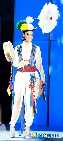 【서울=뉴시스】신동립 기자 = 2010 미스코리아 진 정소라(20·고려대 국제어문학부1)의 파격 전통패션이 주목받고 있다.&nbsp; 2011 미스유니버스 선발대회에 참가 중인 정소라는 7일 브라질 상파울루 크레디카드 홀에서 주관방송사인 미국 NBC TV가 녹화한 미스유니버스 전통의상 쇼에 북을 든 농악 한복차림으로 등장했다. 국제미인뽑기대회에 나선 역대 미스코리아가 입은 조선의 왕비 또는 기생 패션이 아니었다.&nbsp; 이 풍물놀이 옷은 퍼레이드 때 입기로 돼있었다. 대회 프로그램이 바뀌면서 전통옷을 선보일 기회가 한 번으로 줄자 정소라는 함께 준비해간 소례복 당의 대신 이것을 택했다.&nbsp; 정소라의 변종 농악대원복은 얇고 비치는 소재의 홑저고리, 말군 바지, 거들 치마, 바지, 등걸이 배자를 응용한 조끼로 이뤄졌다. 허리선이 드러난 짧은 홑저고리와 조끼, 그리고 바지의 트임으로 신비로운 분위기를 강조했다.&nbsp;&nbsp; 당초 거리 행진을 염두에 둔만큼 액세서리들도 화려하다. 개최국 브라질 국기의 3색 꽃과 타조털 부포를 단 상모, 노리개와 귀주머니 등은 매듭 기능전수자 심영미(65)씨와 자수 명장 이승희(54)씨의 작품이다.&nbsp;&nbsp; 정소라에게 이 옷을 지어준 한복 패션디자이너 김은경(42·은채)씨는 "상모 아이디어를 낸 정소라의 뜻에 맞춰 한국적인 오방색, 농악의상을 모티브로 현대적인 해석을 시도해 한복의 모던한 세련미를 강조했다"면서 "미스유니버스의 콘셉트가 섹시 쪽으로 흐르는 트렌드로 감안했다"고 밝혔다. "정형화된 한복 특유의 색상에서 벗어나 세련되고 다양한 색감을 보여주고, 한복 역시 때와 장소에 따라 창조적인 변화가 가능한 옷임을 알려주고 싶었다"는 것이다.&nbsp; 정소라는 12일 추석 밤 9시(현지시간) 크레디카드홀에서 제60회 미스유니버스 타이틀을 놓고 각국 대표미녀 88명과 경염한다.&nbsp; reap@newsis.com&nbsp;&nbsp; 