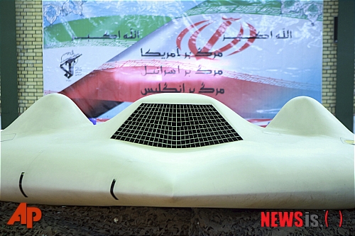 8일 이란 국영방송에 공개된 미 무인정찰기 RQ-170 '센티넬'의 모습. 이란은 전자공격을 통해 무인정찰기를 격추했다고 발표했다. 뒤쪽 배경의 이란 국기 위에는 "미국 망해라" "이스라엘 망해라" 영국 망해라" 등의 글이 쓰여져 있다. <테헤란=AP/뉴시스>