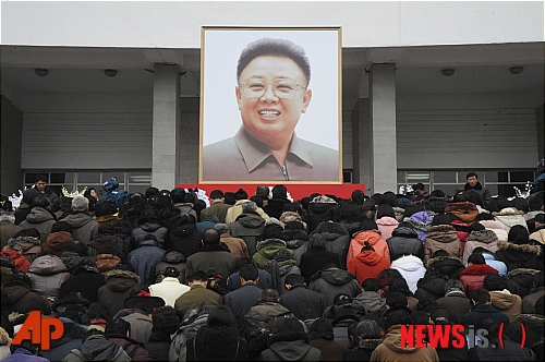 【평양=AP/뉴시스】평양 시민들이 21일 평양실내체육관 앞 광장에 내걸린 김정일 북한 국방위원장의 대형 사진 앞에 모여 애도를 표하고 있다.