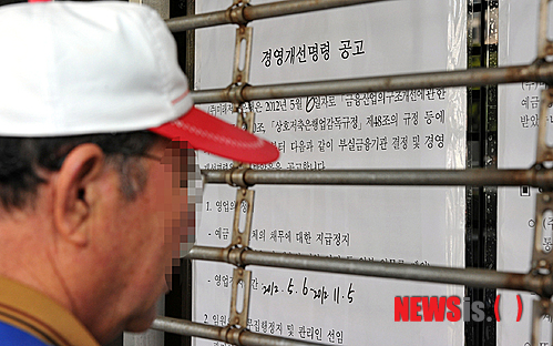 【제주=뉴시스】강재남 기자 = 6일 미래저축은행에 대한 영업정지가 결정되자 이날 오전 제주시 미래저축은행 본점을 찾은 한 고객 넘어로 은행 입구에 붙은 경영개선명령 공고문이 보이고 있다.&nbsp; hynikos@newsis.com