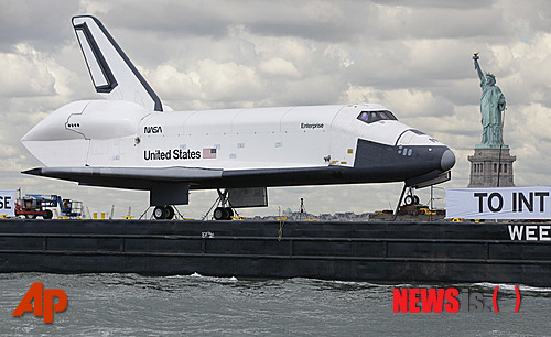 【뉴욕=AP/뉴시스】미 우주왕복선 엔터프라이즈호가 바지선에 실려 자유의 여신상 부근을 거쳐 최종 목적지인 인트레피드 해양항공우주 박물관으로 향하고 있다. 미 항공우주국(NASA)은 지난해 우주왕복선 프로그램을 중단했다.