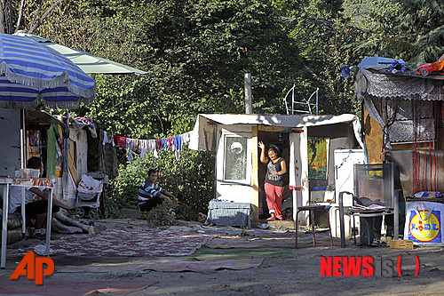 【파리=AP/뉴시스】파리 교외 에브리에서 27일 집시 달동네가 철거되는 동안 다른 집시족들이 허름한 집에 쉬고 있다. 유럽에서 가장 천대받은 소수파인 집시족 로마는 대도시 주변에서 수도 시설도 없이 움막집 등서 생활하고 있다. 그들은 구걸로 연명하기 십상이다.