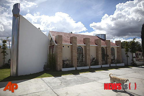 【파추아(멕시코) =AP/뉴시스】9일 멕시코 파추아주에 있는 한 공동묘지에 서있는 마약 카르텔 제타스의 두목 에리베르토 라스카노의 묘 앞에 개 한마리가 서성거리고 있다. 7일 사살된 라스카노가 생전에 지은 이 묘는 그가 한 때 헌금을 했다는 성당의 모형을 본 떠 만든 것이다.