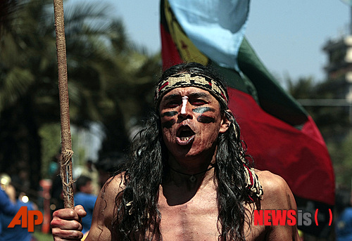 【산티아고(칠레)=AP/뉴시스】마푸체 원주민의 복장을 한 칠레 시위대의 한 사람이 15일 토지와 자치권을 요구하는 산티아고 시내의 시위에 참가하고 있다. 3000명의 마푸체 시위대 틈에 낀 복면한 폭력배들 때문에 경찰은 최루탄과 물대포로 이들을 진압했다고 밝혔다.
