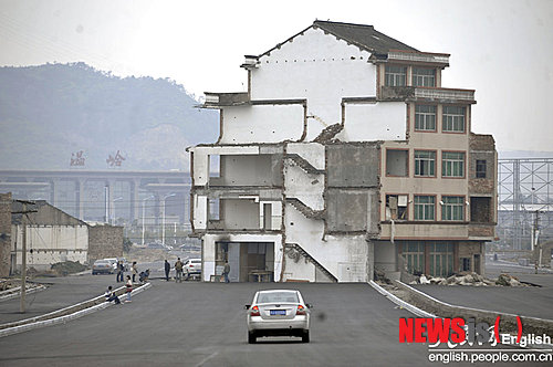 【서울=뉴시스】중국 저장(浙江)성 원링(溫嶺)시에 있는 기차역으로 향하는 고속도로에 5층짜리 아파트가 서 있다. 노부부는 정부의 이주 보상안에 불만이 있어 이사하지 않고 계속 살고 있다고 중국 인민일보(人民日報)가 22일(현지시간) 보도했다. 도로가 정식으로 개통되지 않았지만, 차량은 이 도로를 지나갈 때 이 집을 돌아가야 한다고 이 신문은 전했다. (사진 출처: 인민일보 인터넷판)  