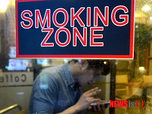 【서울=뉴시스】박상훈 기자 = 오는 8일부터 150㎡ 이상 면적의 음식점에서 흡연구역이 사라지고 별도로 설치된 흡연실에서만 담배를 피울 수 있게 된다. 4일 오후 서울 충무로 한 카페에서 시민이 담배를 피우고 있다. 커피전문점 등 일부 음식점에 설치된 흡연석과 같이 '흡연구역이 유리벽 등으로 천장부터 바닥까지 차단돼 담배연기가 다른 공간으로 흘러가지 못하도록 차단하는 설비를 갖춘 경우' 해당 흡연석을 당분간 흡연실로 간주해 운영할 수 있다. 그러나 전면 금연이 시행되는 2015년 1월 1일부터는 모든 흡연석을 폐쇄해야 한다. hyalinee@newsis.com