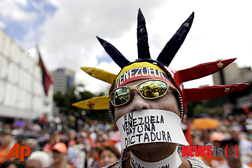 【카라카스=AP/뉴시스】12일 카라카스에서 열린 반정부 시위에 참가한 한 시위자가 입에 "베네수엘라에는 독재정권이 있다"고 쓰인 글귀를 달고 나왔다. 베네수엘라 야당은 우고 차베스 대통령의 취임식 연기가 합법적이라는 대법원의 판결에 불복해 이 문제를 남미 인권재판소에 회부할 움직임이다. 2021.12.27.