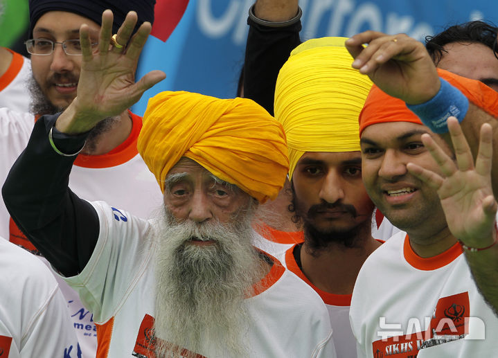 [홍콩=AP/뉴시스]인도의 파우자 싱(왼쪽)이 102세이던 2013년 2월24일 홍콩에서 10㎞ 마라톤을 완주한 뒤 손을 흔들고 있다. 이 경기를 끝으로 은퇴했던 세계 최고령 마라토너 싱은 14일 그가 살던 마을 비아스에서 길을 건너던 중 뺑소니 차량에 치어 114세로 숨졌다. 2025.07.15.