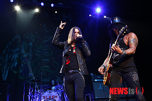 【서울=뉴시스】이재훈 기자 = 깁슨 레스폴 기타는 포효하거나 그르릉거렸다. 짐승 기타리스트 슬래시(48)가 조련하는 기타다웠다.&nbsp;&nbsp; 자신의 상징처럼 된 영국의 신사 모자 같은 '탑햇(top hat)'과 선글라스를 쓰고 미키 마우스가 그려진 검은 색 민 소매 티셔츠를 입은 슬래시가 매만질 때마다 기타는 울부짖었다.&nbsp;&nbsp; 특히, '로켓 퀸(Rocket Queen)'을 연주할 때 그의 짐승다움이 도드라졌다. 육중한 팔 근육이 꿈틀거리면서 기타를 튕길 때 짐승을 넘어 날 것의 무엇인가를 보여줬다.&nbsp; 중국 전통 악기 비파를 연주하듯 기타를 거의 수직으로 세워서 매만지는 그의 모습이 전면에 드러났다. 이 곡을 연주한 총 15여분 중 약 10분을 자신의 밴드 앞에 홀로 나와 실력을 과시했다. 손가락으로 누르는 대신 슬라이드 바를 사용해 줄 위를 매끄럽게 타는 기타 주법인 슬라이드를 잠깐 선보이기도 했다.&nbsp;&nbsp; 2011년 첫 단독 공연 이후 약 2년2개월 만에 내한, 9일 밤 서울 광장동 유니클로 악스에서 2번째 솔로 공연을 선보인 슬래시 무대의 절정은 '로켓 퀸'을 비롯해 그가 몸 담은 미국의 세계적인 헤비메탈 밴드 '건스 앤 로지스(Guns N' Roses)'의 곡들을 들려줄 때였다.&nbsp; '헤일로(halo)'로 포문을 여는 등 지난해 발매한 2번째 솔로 앨범 '아포칼립틱 러브'를 기념하는 투어였지만 건스 앤 로지스의 노래들이 흘러나올 때 1500여 팬들의 환호성도 더 크게 터져나왔다.&nbsp;&nbsp; 역대 최고의 기타 도입 리프(riff) 중 하나로 손꼽히는 건스 앤 로지스의 '스위트 차일드 오 마인(Sweet Child O' Mine)'는 화룡점정이었다. 2층 지정석의 팬들도 모두 일어났다. 노래 뿐만 아니라 전주, 간주, 후주의 멜로디까지 '떼창'하는 마니아들의 모습이 인상적이었다.&nbsp; 앙코르 역시 본 공연 못지 않았다. '웰컴 투 더 정글(Welcome to the Jungle)' '파라다이스 시티(Paradise City) 등 역시 슬래시의 기타 리프를 통해 귀에 익은 건스 앤 로지스의 곡들도 공연장은 들썩였다.&nbsp; 실제 슬래시는 1980년대 말부터 1990년대 초까지 건스 앤 로지스의 전성기의 주역이다. 결성 24년 만인 지난 2009년 12월 건스 앤 로지스의 첫 내한 공연은 명성에 살짝 못 미친 감이 있었다. 팬들을 무려 2시간20분 간 기다리게 하는 등 악동 기질은 여전했으나 원년 멤버가 보컬 액슬 로즈(51)밖에 남아 있지 않았다는 점에서 어찌 보면 당연한 수순이었다.&nbsp;&nbsp; 슬래시의 이날 공연은 일면 건스 앤 로지스의 내한공연 때보다 더 건스 앤 로지스의 공연 같았다는 점에서 록기운이 충만했다.&nbsp;&nbsp; 슬래시 뿐 아니라 밴드 자체의 실력도 상당했다. 특히 지난 슬래시의 첫 내한공연 때도 함께 했던 보컬 마일스 케네디(44)는 특유의 쇳소리로 고음을 무난히 소화하면서 화려한 무대 매너까지 뽐냈다.&nbsp; 가타부타 특별한 말을 꺼내지 않은 슬래시는 약 2시간 남짓한 공연 내내 카리스마를 잃지 않았을 뿐 아니라 쉰에 가까운 나이에도 섹시함을 자랑했다. 슬래시를 포함한 밴드의 강렬한 연주가 끝난 뒤 잔향처럼 남은 하울링 사운드가 청중의 아쉬운 발길을 배웅했다.&nbsp; 이날 오프닝 무대는 시원하고 강렬한 연주력이 인상적인 펑크록 밴드 '옐로우 몬스터즈'가 꾸몄다. 모던 록 1세대 밴드로 통하는 '델리 스파이스'의 드러머 최재혁(38)과 '마이 앤트 메리'의 베이시스트 한진영(37), 펑크 밴드 '검엑스'의 이용원(33)이 의기투합한 밴드는 슬래시와 기념사진을 남기기도 했다.&nbsp; 애초 슬래시와 옐로우 몬스터즈는 이날 세계적인 얼터너티브 메탈밴드 '데프톤스'와 함께 '메탈페스트 2013'을 펼치려고 했다. 그러나 데프톤스가 팀 사정으로 내한을 포기하면서 슬래시 단독 공연의 모양새를 갖추게 됐다. 하지만 이날 공연은 데프톤스의 불참에 대한 아쉬움을 충분히 달랠 만했다.&nbsp; 공연이 끝난 뒤 자신의 기타 피크를 객석에 나눠준 슬래시는 자신의 트위터에 "서울의 오늘밤은 군중이 죽여줬다! 심하게 좋은 시간이었다!"(KILLER crowd in Seoul tonight! Good fxxking times!)고 남겼다. 내한 공연 직전 e-메일을 통해 "한국팬들은 지금껏 내 공연을 찾아온 팬들 중 최고"라고 전했던 그의 말이 하울링처럼 남았다.&nbsp; <사진> 액세스 ENT 제공&nbsp;&nbsp; realpaper7@newsis.com 