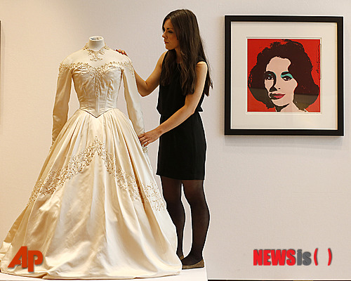 【런던=AP/뉴시스】경매회사 크리스티의 직원이 19일(현지시간) 영국 런던에 있는 크리스티 본사에서 디자이너 헬렌 로스가 제작한 여배우 엘리자베스 테일러의 첫 웨딩드레스를 전시하고 있다. 크리스티가 120년 동안 진행한 팝 문화 경매에서 판매할 이 웨딩스레스는 30만~50만 파운드에 낙찰될 것으로 예상된다. 2013.06.22 