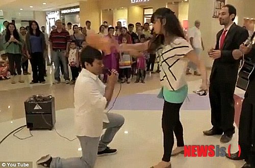 【서울=뉴시스】두바이의 한 쇼핑몰에서 공개 구혼을 했다 여성으로부터 머리를 가격당해 쓰러지는 한 청년의 모습을 담은 동영상이 유튜브에서 큰 인기를 얻고 있다. 사진은 공개 프로포즈에 당황한 여성이 악사의 우클레레로 청혼하는 남자의 머리를 내려치는 모습. <사진 출처 : 英 데일리 메일> 2013.08.27
