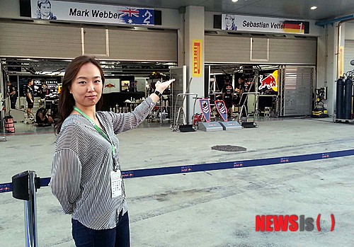 【영암=뉴시스】송창헌 기자 = 전남 영암 F1 경주장 내 팀별 피트(Pit)에 설치된 배너판을 제작한 카툰 작가 박지연씨가 3일 레드불 팀 피트 앞에서 완성된 작품을 배경으로 환하게 웃고 있다. 2013.10.04. goodchang@newsis.com