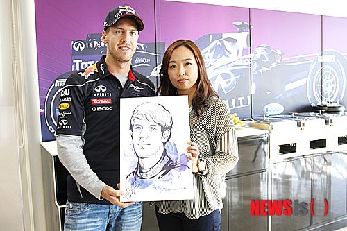 【영암=뉴시스】송창헌 기자 = 전남 영암 F1 경주장 내 팀별 피트(Pit)에 설치된 배너판을 직접 제작한 카툰 작가 박지연씨가 3일 '디펜딩 챔피언' 세바스찬 베텔에게 자신이 제작한 캐리커쳐를 선물한 뒤 기념사진을 찍고 있다. 2013.10.04. (사진=F1 조직위원회 제공) goodchang@newsis.com