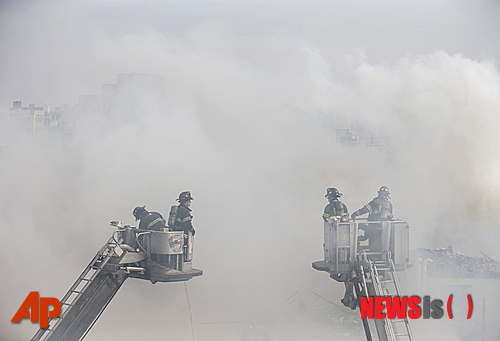 【뉴욕=AP/뉴시스】12일 뉴욕 이스트할렘 116번가 인근에 있는 건물이 폭발로 붕괴한 이후 화재가 발생, 연기가 치솟고 있는 가운데 소방관들이 진화에 나서고 있다. 이날 폭발로 건물 최소 한 곳이 무너지고 다수의 사상자가 발생했다. 2014.03.13