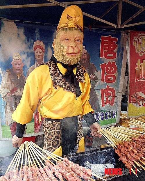 【서울=뉴시스】최근 중국 후베이(湖北)성 우한(武漢)에서 봄꽃 축제가 열린 가운데 한 노점상이 길거리에 '손오공' 분장을 하고 양꼬치를 팔고 있다. 중국 고전 명작 '서유기'에서 삼장법사를 보호하던 '손오공'이 스승의 고기로 만든 꼬치를 파는 어이 없는 일이 일어난 가운데 고전 명작을 왜곡하고 전통 문화를 망친 상술이라는 비난이 일고 있다.(사진출처: 차이나 데일리) 