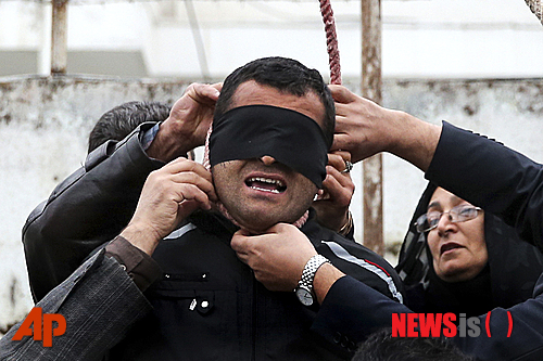 【테헤란=AP/뉴시스】이란 국영 뉴스통신 ISNA가 지난 15일(현지시간) 공개한 사진으로 사메레흐 알리네자드(오른쪽)와 그의 남편 압돌그하니(왼쪽)가 눈을 가린 빌랄의 목에 걸린 올가미를 빼고 있다. 빌랄은 이란 북부 누르에서 이들의 아들 압둘라 호세인자데를 살해한 혐의로 사형선고를 받아 이날 사형될 예정이었으나 피해자 부모가 빌랄의 사형집행 전 빌랄을 용서하면서 간신히 목숨을 구했다. 2014.04.18