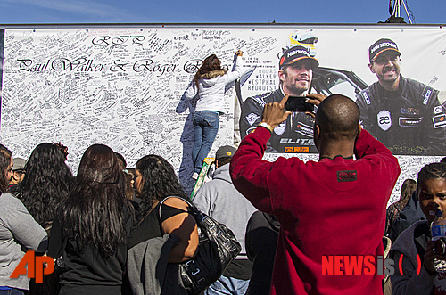 【로스앤젤레스=AP/뉴시스】2013년 12월8일 폴 워커의 팬들이 캘리포니아 발렌시아가에서 추모 집회를 열고 교통사고로 숨진 폴 워커와 친구 로저 로다스를 위해 서명을 하고 있다. 로다스의 미망인은 이 사고가 차체 결함 때문이라며 12일 로스앤젤레스 법원에 포르쉐 자동차를 상대로 고소장을 냈다. 2014.5.13&nbsp;&nbsp; 