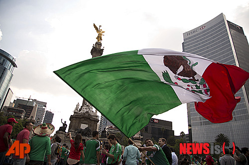 A Mexico soccer fan waves the Mexican national flag while he celebrates his team's tie with Brazil in a World Cup soccer match, in Mexico City, Tuesday, June 17, 2014. Mexico claimed a deserved point against Brazil in a largely frustrating Group A game which finished 0-0 at Estadio Castelao in Fortaleza, Brazil. (AP Photo/Moises Castillo)