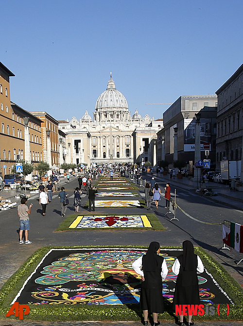 【로마=AP/뉴시스】이탈리아 로마 성 베드로 광장 인근 도로 비아 델라 콘칠리아치오네에서 꽃 박람회 인피오라타가 열리는 가운데 그 뒤로 교황청 건물이 보인다. 로마 교황청이 공식적으로 국제퇴마사협회를 인정했다. 교황청 기관지 로세르바토레 로마노는 3일(현지시간) 교황청 성직자성이 이 협회의 정관을 허가하고 교회법에 따라 이 협회를 인정했다고 보도했다. 2014.07.05