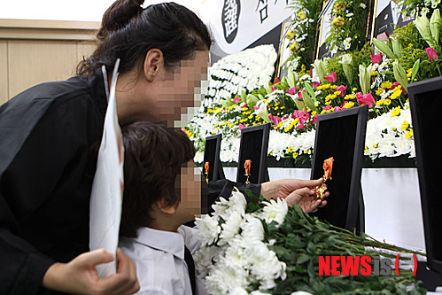 【춘천=뉴시스】한윤식 기자 = 20일 광주 헬기추락사고 순직한 안병국(38.항공정비사) 소방관 아들 안정환(8) 어린이가 강원 춘천시 동내면 거두리 효장례문화에 마련된 합동분향소에서 엄마와 함께 아빠의 훈장을 만지며 슬픔에 잠겨 있다. 2014.07.20&nbsp; ysh@newsis.com 