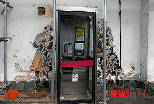 【런던=AP/뉴시스】잉글랜드 서부도시 첼트넘에 있는 유명 거리 화가 뱅크시의 작품이 1일(현지시간) 은색과 적색 페인트로 한 낙서에 훼손된 모습. 영국 지역보존운동까지 촉발시킨 이 벽화 ‘스파이 부스’가 훼손됐다. 이 벽화는 지난 4월 여국 첩보기구인 정보통신본부(GCHQ)의 본부가 있는 잉글랜드 서부도시 첼트넘의 한 공중전화박스 뒤쪽 벽에 나타났다. 이후 이 건물 주인이 벽을 해체해 팔려고 하자 이 벽화를 지키기 위한 지역보전단체가 구성됐다. 이 운동을 벌이고 있는 안젤라 데 수자는 한 현지 사업가가 이 벽화를 구입해 보존하기로 했다고 밝혔으나 이날 이 벽화가 낙서로 뒤덮였다. 데 수자는 이 단체 소속 단원들이 즉각 벽화 복원에 나섰다고 밝혔다. 뱅크시의 작품들은 경매에서 나오면 최소 180만 달러가 넘는 가격에 팔리자 최근 일부 야외에 있는 작품들이 벽면에서 해체돼 경매에서 팔렸다.