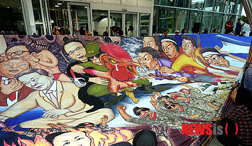 【광주=뉴시스】배동민 기자 = 8일 오후 광주 북구 광주시립미술관 앞에서 광주비엔날레 창설 20주년 기념 특별전 개막식이 열렸다. 홍성담 작가의 걸개그림 '세월오월'이 박근혜 대통령을 풍자했다는 이유로 작품 전시가 유보되자 참여작가와 지역 예술인들이 대형 프린트 작품을 펼치며 항의하고 있다. 2014.08.08&nbsp; guggy@newsis.com