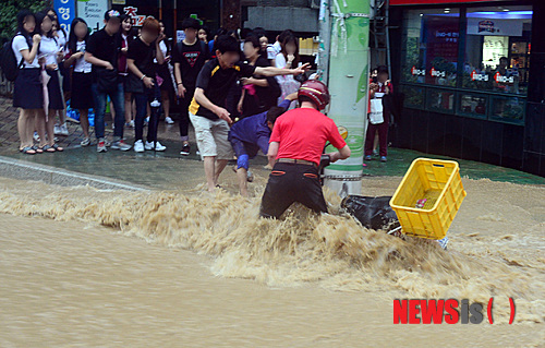 【부산=뉴시스】 하경민 기자 = 기록적인 폭우가 쏟아진 25일 오후 부산 북구 구포3동의 한 사거리에 엄청난 양의 급류가 도로를 뒤덮은 가운데 오토바이 1대가 급류에 휩쓸리자 시민들이 빼져나올 수 있게 힘을 보태고 있다. 2014.08.25.&nbsp; yulnetphoto@newsis.com 
