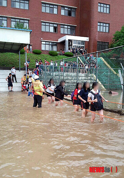 【부산=뉴시스】 하경민 기자 = 기록적인 폭우가 쏟아진 25일 오후 부산 북구 양덕여중 뒷산에서 엄청난 양의 물이 쏟아져 학교 건물 3개 층이 침수된 가운데 400여 명의 학생들이 소방대원들이 설치된 안전로프를 잡고 대피하고 있다. 2014.08.25. (사진=북부소방서 제공)&nbsp; yulnetphoto@newsis.com 