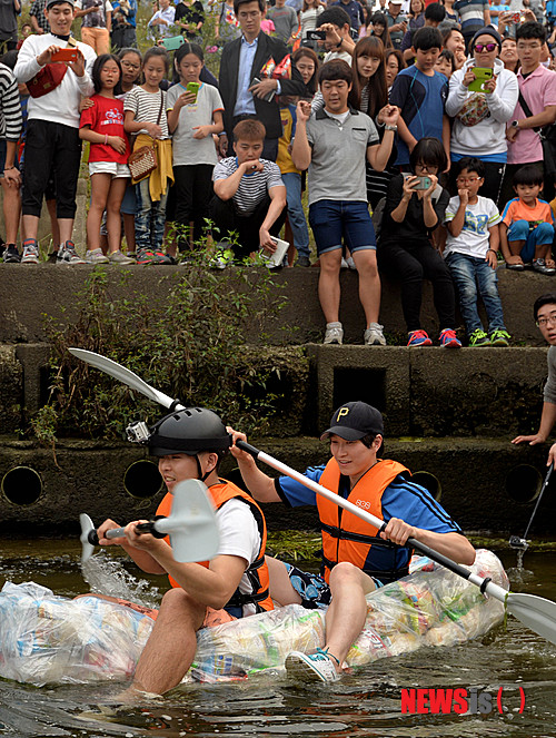 【서울=뉴시스】박문호 기자 = 제과업계의 과대포장을 꼬집기 위해 질소 충전된 과자 봉지 150여 개를 묶어 '과자 뗏목'을 만든 대학생들이 28일 오후 서울 송파구 잠실한강공원에서 직접 노를 저어 한강을 건너고 있다. 2014.09.28.&nbsp; go2@newsis.com