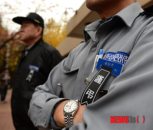 【서울=뉴시스】조수정 기자 = 최근 아파트 한 입주민으로부터 모욕을 당한 한 경비노동자가 분신, 30여일만에 사망한 것과 관련, 8일 서울 압구정동 신현대아파트에서 동료 경비노동자들과 민주노총 조합원, 야당 당원 등 참석자들이 아파트의 입주민대표자회의의 사과와 대책을 촉구하는 기자회견을 하고 있다. 그 뒤로는 근무중인 이 아파트 경비노동자들이 가슴에 근조 리본을 달고 기자회견을 바라보고 있다. 이 아파트에서 분신한 경비노동자는 한 입주민의 비인간적 대우에 지난 10월 7일 분신해 11월 7일 사망했다. 2014.11.08.&nbsp;&nbsp;&nbsp; chocrystal@newsis.com