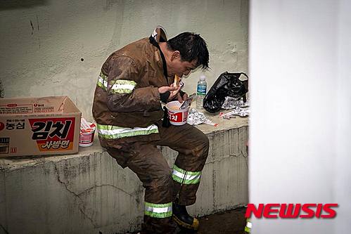[부산=뉴시스] 하경민 기자 = 차량 570여 대를 태워 35억원(소방 추산) 상당의 피해를 내 부산 중고자동차 매매단지 화재현장에서 밤샘 진화작업 이후 구석에서 컵라면으로 끼니를 해결하는 소방관의 모습이 담긴 사진이 공개돼 감동을 주고 있다. 사진은 부산경찰청 페이스북을 통해 공개된 컵라면 먹는 소방관의 모습. 2015.04.03. (사진=부산경찰청 제공) yulnetphoto@newsis.com