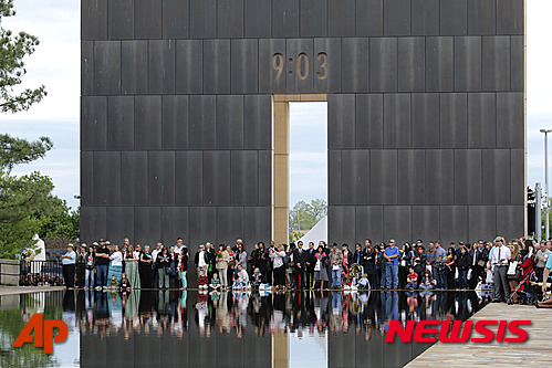 【오클라호마시티=AP/뉴시스】168명의 희생자를 낸 미국 오클라호마시티 폭탄 테러 사건이 일어난 지 20년이 되는 19일(현지시간) 파괴된 연방 청사가 있던 자리에서 추모 행사가 열렸다. 오클라호마 시티 국립 추모 공원에서 개최된 이날 행사에는 빌 클린턴 전 대통령과 메리 펄린 오클라호마 주지사 및 시민 약 2500명이 참석했다. 행사가 열린 가운데 테러 발생 시간을 의미하는 '9:03' 게이트 조형물 앞에서 시민들이 서있다. 2015.04.20 