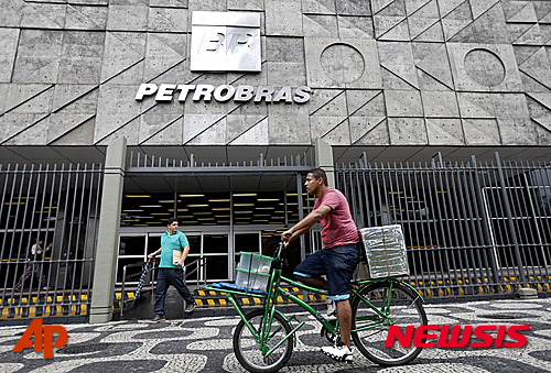 【리우데자네이루=AP/뉴시스】브라질 남성이 22일(현지시간) 리우데자네이루에 있는 페트로브라스 본사 앞에 자전거를 타고 지나가고 있다. 브라질 국영 석유회사 페트로브라스가 부풀린 계약과 장기적 리베이트로&nbsp; 21억 달러의 손해를 봤다. 브라질 연방검찰은 이를 브라질 최대 부패 사건으로 보고 계속 수사를 진행하고 있으며 수사가 확대되고 있다고 밝혔다. 2015.04.23
