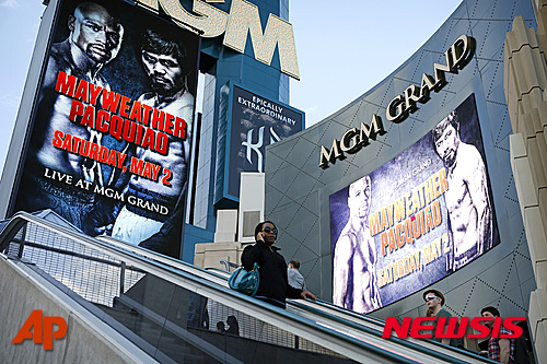 People ride an escalator by signs advertising the Mayweather Pacquiao fight at the MGM Grand Wednesday, April 22, 2015, in Las Vegas. (AP Photo/John Locher)