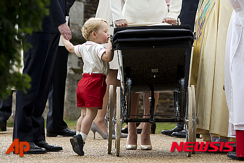 【샌드링엄=AP/뉴시스】영국 윌리엄 왕세손 부부의 첫째인 조지 왕자가 5일(현지시간) 유모차에 타고 있는 자신의 동생 샬럿 공주를 보기 위해 까치발을 하고 있다. 이날 샬럿 공주의 세례식이 영국 동부 샌드링엄의 성 마리아 막달레나 교회에서 거행됐다. 2015.07.06. 