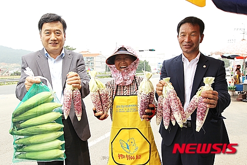 【고성(경남)=뉴시스】신정철 기자 = 경남 고성군은 17일 고성군의 명물로 자리잡은 고성읍 월평리 찰옥수수 판매거리의 농업인들에게 2016경남고성공룡세계엑스포를 홍보하는 앞치마 200장을 전달했다. 옥수수를 상징하는 노란색 바탕에 공룡과 옥수수를 조합한 캐릭터 앞치마를 전달한 김상준 군의원(오른쪽)과 농업인이 기념사진을 촬영했다.2015.07.17.(사진=고성군 제공)&nbsp;&nbsp; photo@newsis.com