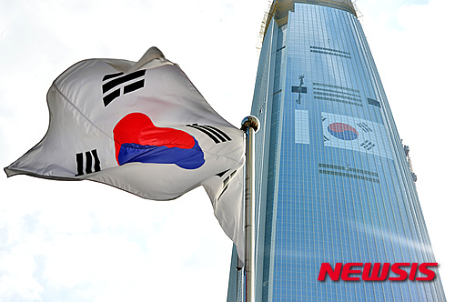 【서울=뉴시스】고승민 기자 = 최근 불거진 형제간의 경영권 분쟁에서 롯데그룹에 대한 일본 국적 논란이 이는 가운데 6일 오전 서울 송파구 롯데월드타워 304미터 지점 70층 주변 창문에 초대형 태극기가 설치되고 있다. 롯데물산은 15일 광복절을 맞아 설치한다고 최근 밝힌 바 있지만 그룹의 '국적 논란'에 대응해 한국 기업 이미지를 고취시키기 위한 것으로 풀이되고 있다. 2015.08.06.&nbsp; kkssmm99@newsis.com