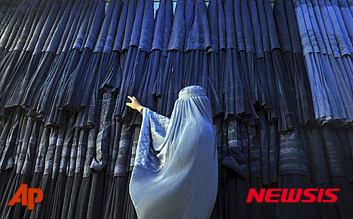 【카불=AP/뉴시스】2015년 9월10일 부르카 복장을 한 무슬림 여성이 아프가니스탄 수도 카불 북부 마자리 샤리프에 있는 상점 앞에서 아프간 전통옷들을 구경하고 있다. 2015.11.19.