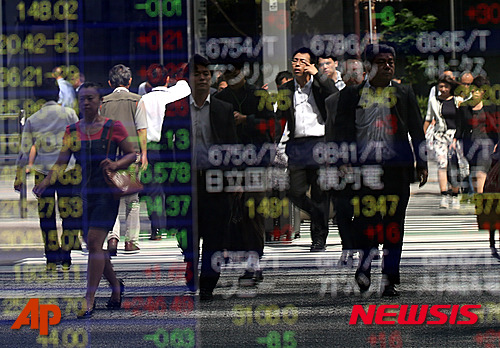 【 도쿄=AP/뉴시스】16일 도쿄 주식시장에서 닛케이225지수(닛케이평균주가)는 전일 대비 145.12포인트(0.81%) 상승한 1만8171.60으로 장을 마쳤다. 사진은 15일 도쿄 중심가의 한 증권사 앞 시황판에 비친 시민들의 모습.2015.09.16