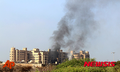 【아덴=AP/뉴시스】예멘 남부 항구도시 아덴에 있는 알카시르 호텔에서 6일(현지시간) 로켓 공격을 받은 후 검은 연기가 피어오르고 있다. 이 호텔에는 칼리드 바하 예멘 총리, 각료, 아랍에미리트연합(UAE)의 군 고위 관계자들이 상주하는 곳으로, 이번 공격으로 18명이 사망했다. 2015.10.06
