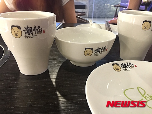 【뉴욕=뉴시스】중국 광둥성(廣東省)에 북한 김정은 조선노동당 제1비서의 얼굴을 풍자한 식당이 화제를 불러 일으키고 있다고 7일 '글로벌웹진' 뉴스로(www.newsroh.com) 가 전했다. 화제의 식당은 지난 1일 중국의 국경절에 개업을 한 해산물 전문식당 '조선(潮仙)'이다. 북한의 공식 국명인 조선(朝鲜)과는 한자가 다르지만 같은 한글 발음으로 다분히 풍자의 의도를 드러내고 있다. 간판엔 '조선'이라는 옥호와 함께 김정은 제1비서로 추정되는 캐리커처가 있고 한글로 '조선 해물찜'이라는 글씨도 써 있다. 식당에 들어서면 인테리어는 물론, 메뉴판과 주방 출입커튼, 그릇, 컵, 커튼 심지어 젓가락 보까지 비슷한 캐릭터가 그려져 시선을 끈다. <사진=Newsroh.com 제공> 