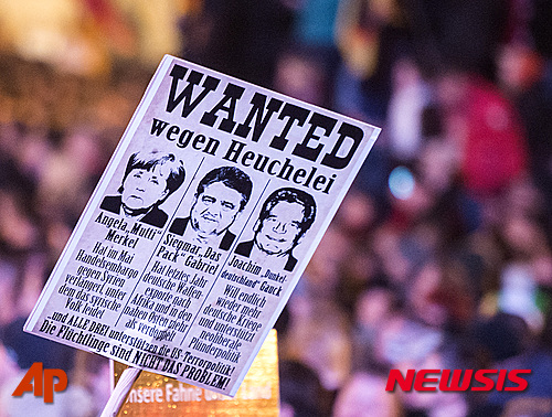 【드레스덴=AP/뉴시스】독일 드레스덴에서 19일(현지시간) 열린 반난민단체 '페기다' 창설 1주년 집회에서 한 참가자가 '현상수배'라고 쓴 팻말을 들고 있다. 팻말에는 난민 수용 정책을 발표한 앙겔라 메르켈 총리, 지그마어 가브리엘 부총리, 요하임 가우크 대통령을 현상수배한다는 내용이 적혀있다. 2015.10.20&nbsp; 