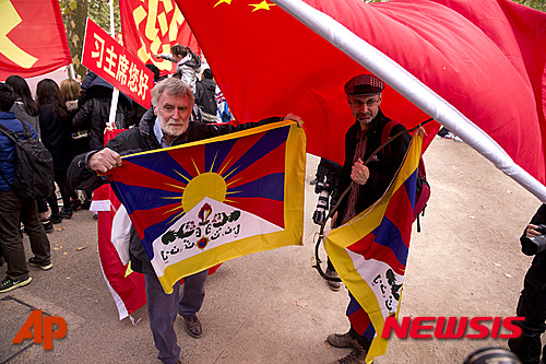 【런던=AP/뉴시스】중국 시진핑(習近平) 중국 국가주석이 영국 국빈 방문 일정을 소화하는 가운데 중국의 인권정책 등에 항의하는 반중 인사들이 런던에 집결해 반대목소리를 냈다. 시 주석 방문의 공식일정 첫날인 20일부터 버킹엄 궁 앞을 포함한 런던 도심 곳곳에는 친중 단체와 반중 시위대가 맞불시위를 벌였다. 버킹엄 궁 앞에서 친중 인사들이 시 주석의 방문을 환영하는 가운데 티베트 독립을 지지하는 단체 시위자들이 티베트 설산사자기를 들고 있다. 2015.10.21&nbsp; 